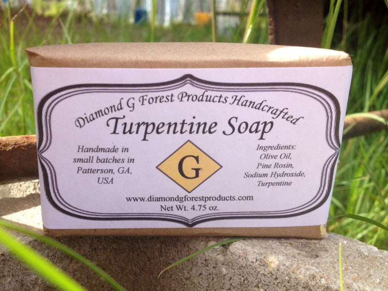 Turpentine Soap shown here is a paper wrapped bar of soap, handcrafted in small batches by Diamond G Forest Products from Olive Oil with their own handcrafted southern Pine Rosin, Sodium Hydroxide, and their 100% Pure Gum Spirits of Turpentine. All natural, dye-free and perfume-free soap for hands and body. Natural pine scent.
